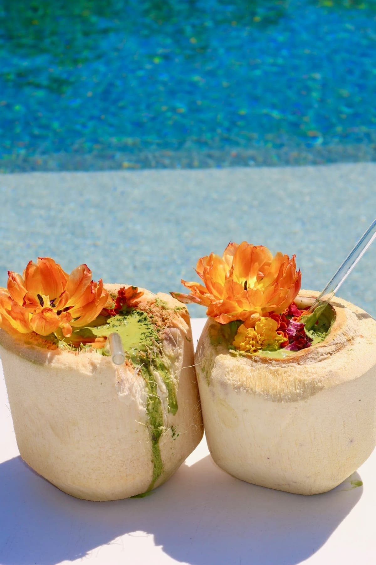 Matcha served in fresh coconuts, topped with orange tulips and marigolds, by the pool